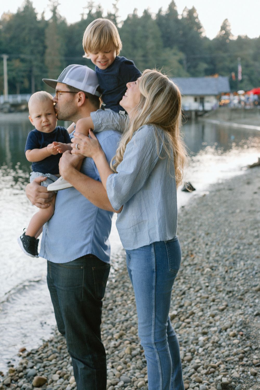 Family of four posing together on a rocky lakeshore during a beautiful sunset evening.