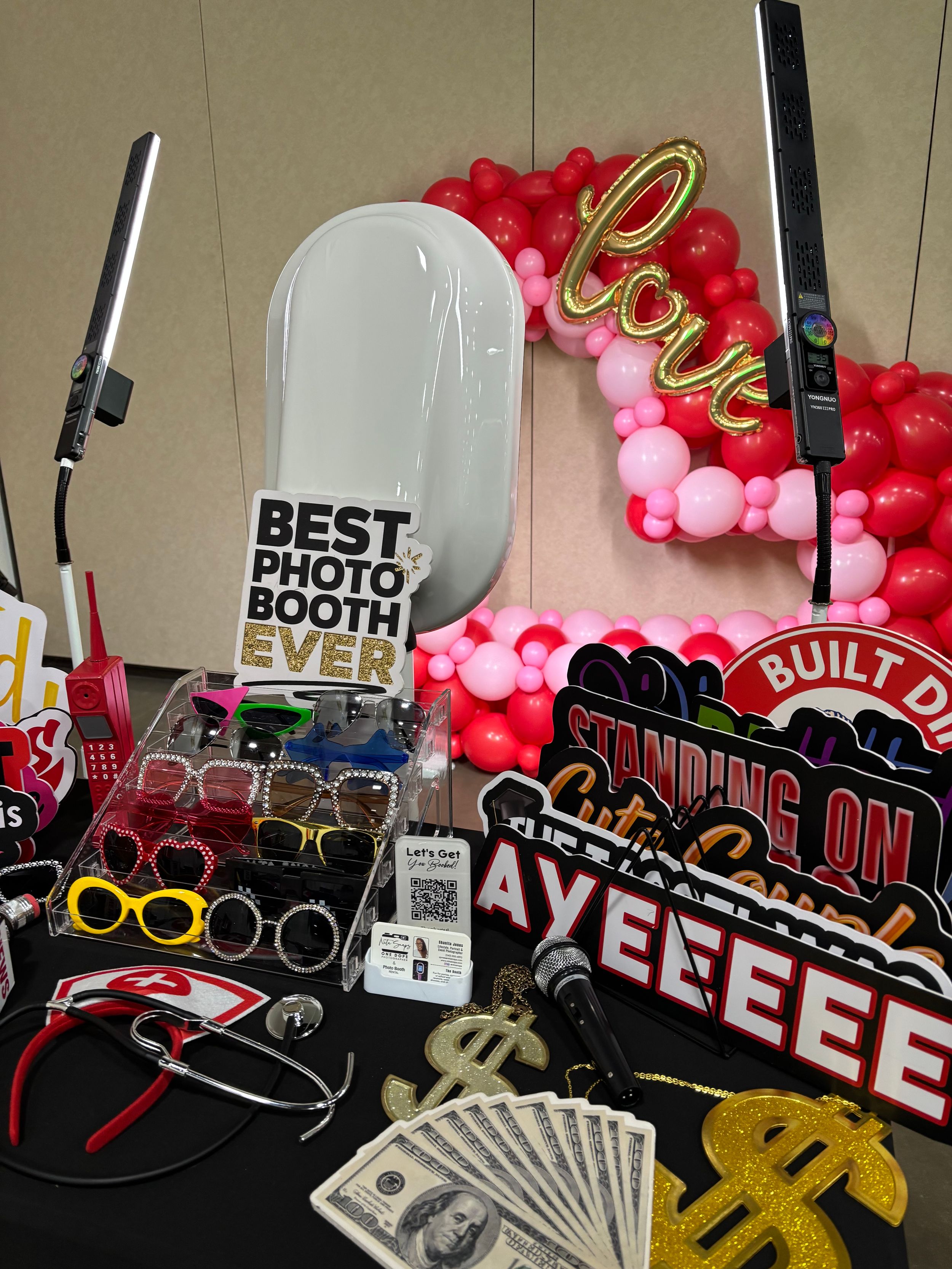 Decorative balloon arch display with graduation-themed props including money, glasses, and celebratory signs.