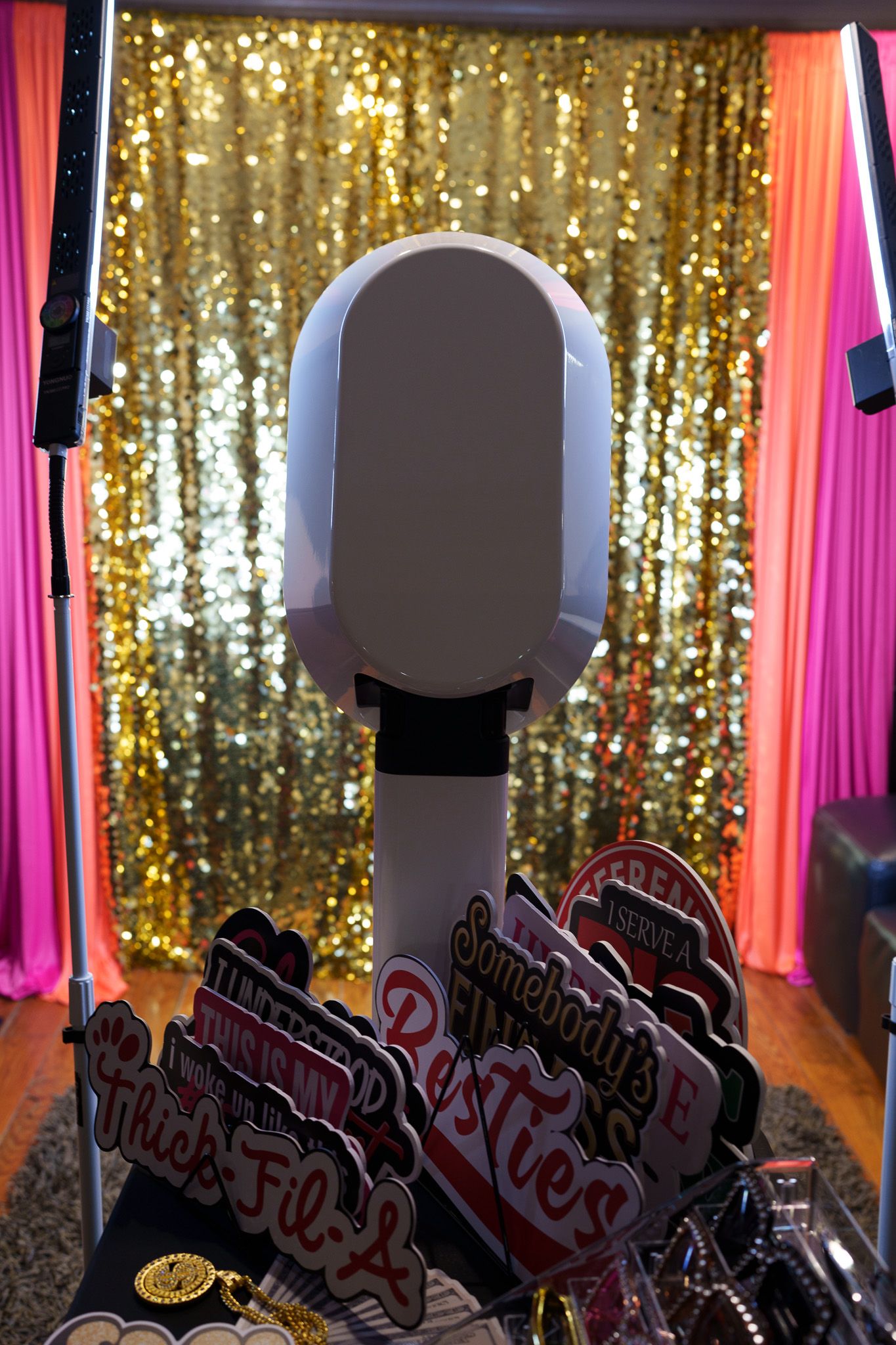 Gold sequin backdrop photo booth setup with props including heart-shaped signs and decorative accessories.