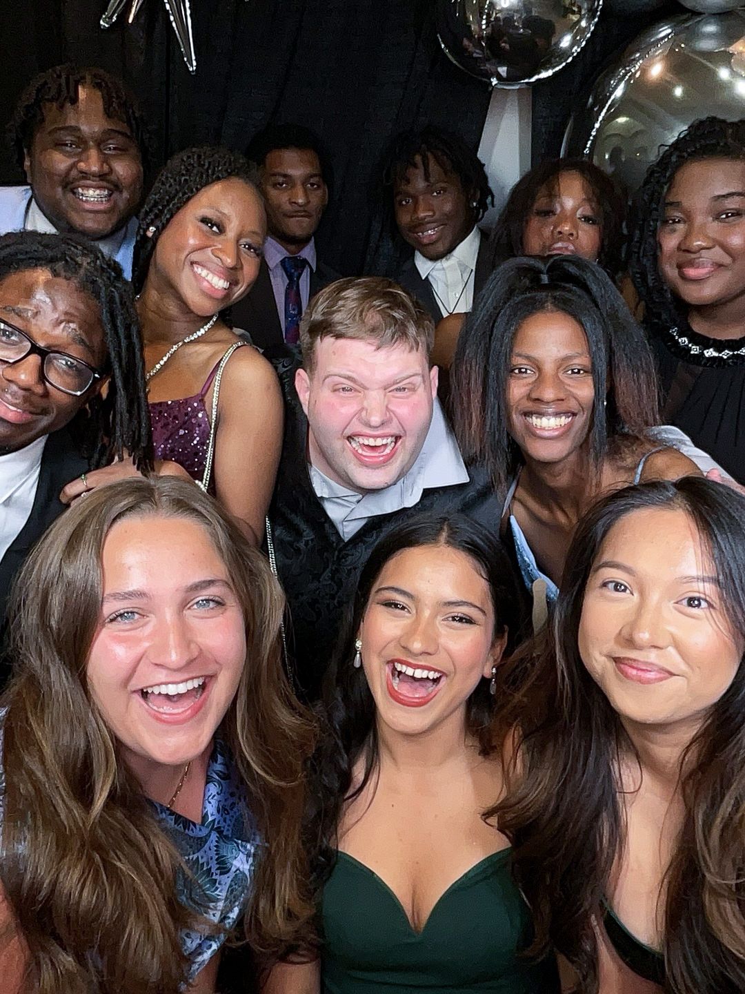 A group of young people smiling and posing together in a casual social gathering photograph.