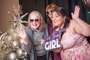 People celebrating at a bachelorette party with pink decor, glitter, and festive decorations in a nighttime setting.