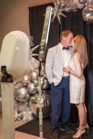 Couple sharing an intimate moment at formal celebration with sparkly silver balloon decorations.
