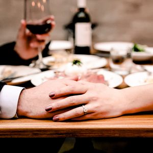 Close-up view of hands resting on a wooden table surface in warm lighting.