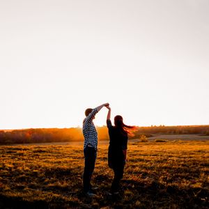 Silhouettes of people walking across a hilltop during golden hour.