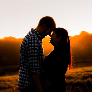 Silhouettes of two people against a dramatic orange sunset backdrop.