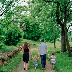 a family of four walking through a lush green field in the spring
