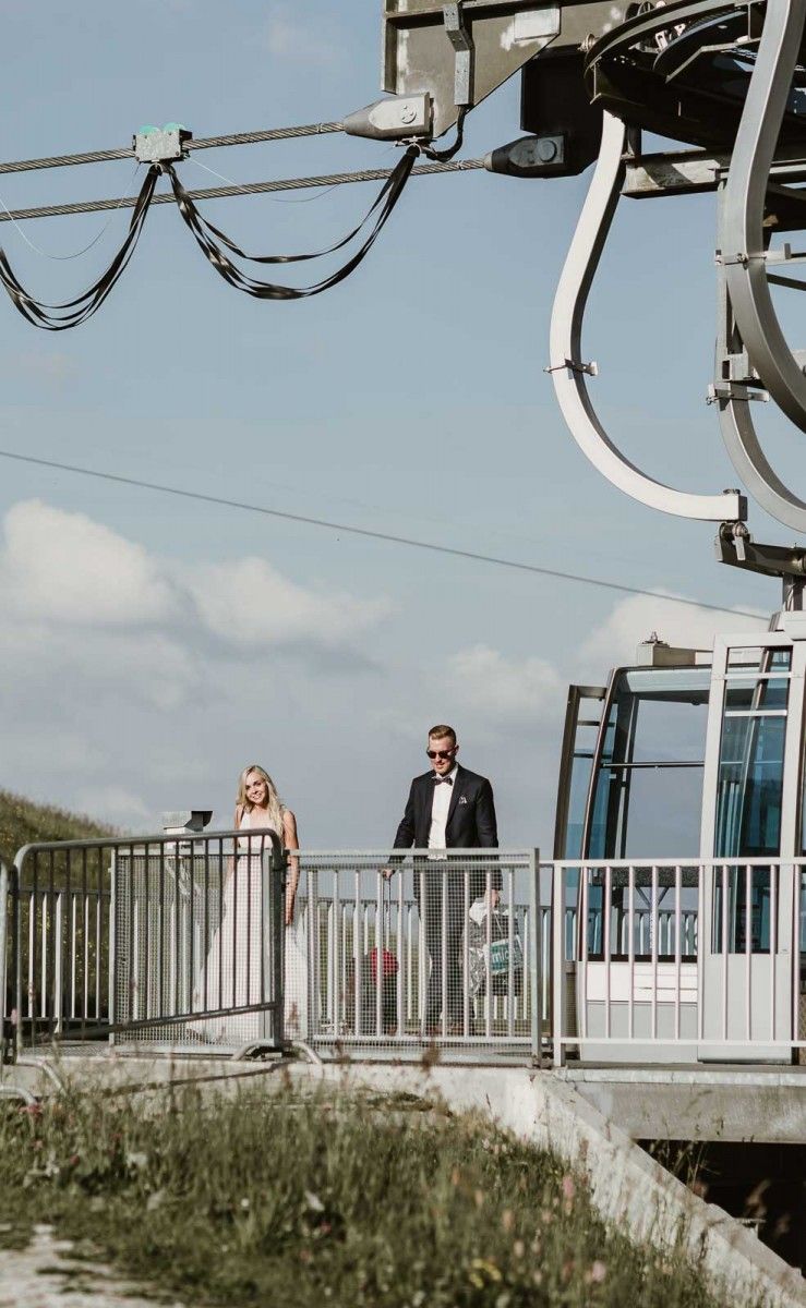 A bride and groom walking off a mountain cable car station platform on their wedding day.