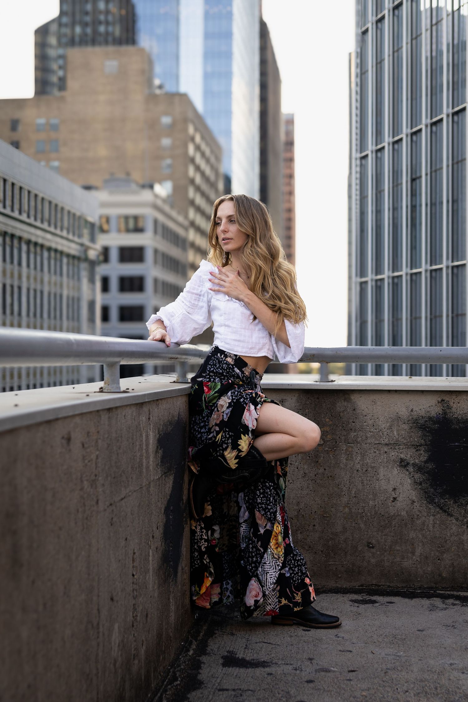 Fashion portrait session on an urban rooftop with city buildings in the background.