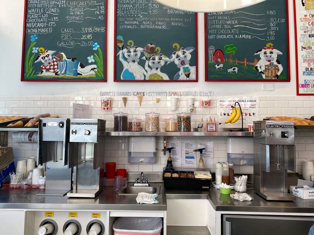 Interior view of ice cream shop counter with menu boards and dispensing machines.