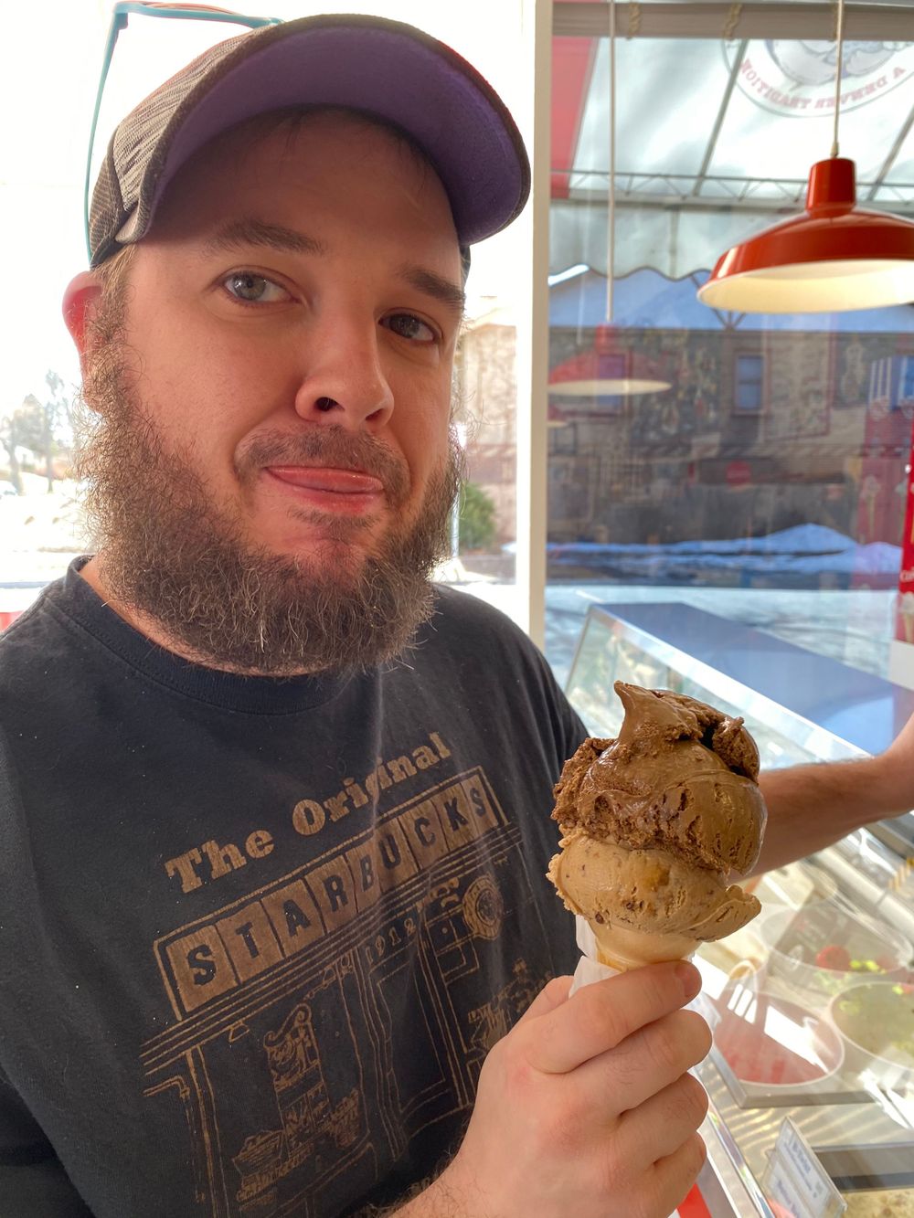 Close-up of large chocolate ice cream cone being held near window.
