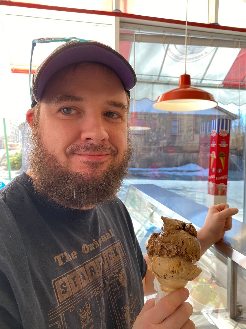 Customer enjoying a chocolate and vanilla ice cream cone inside an ice cream shop.