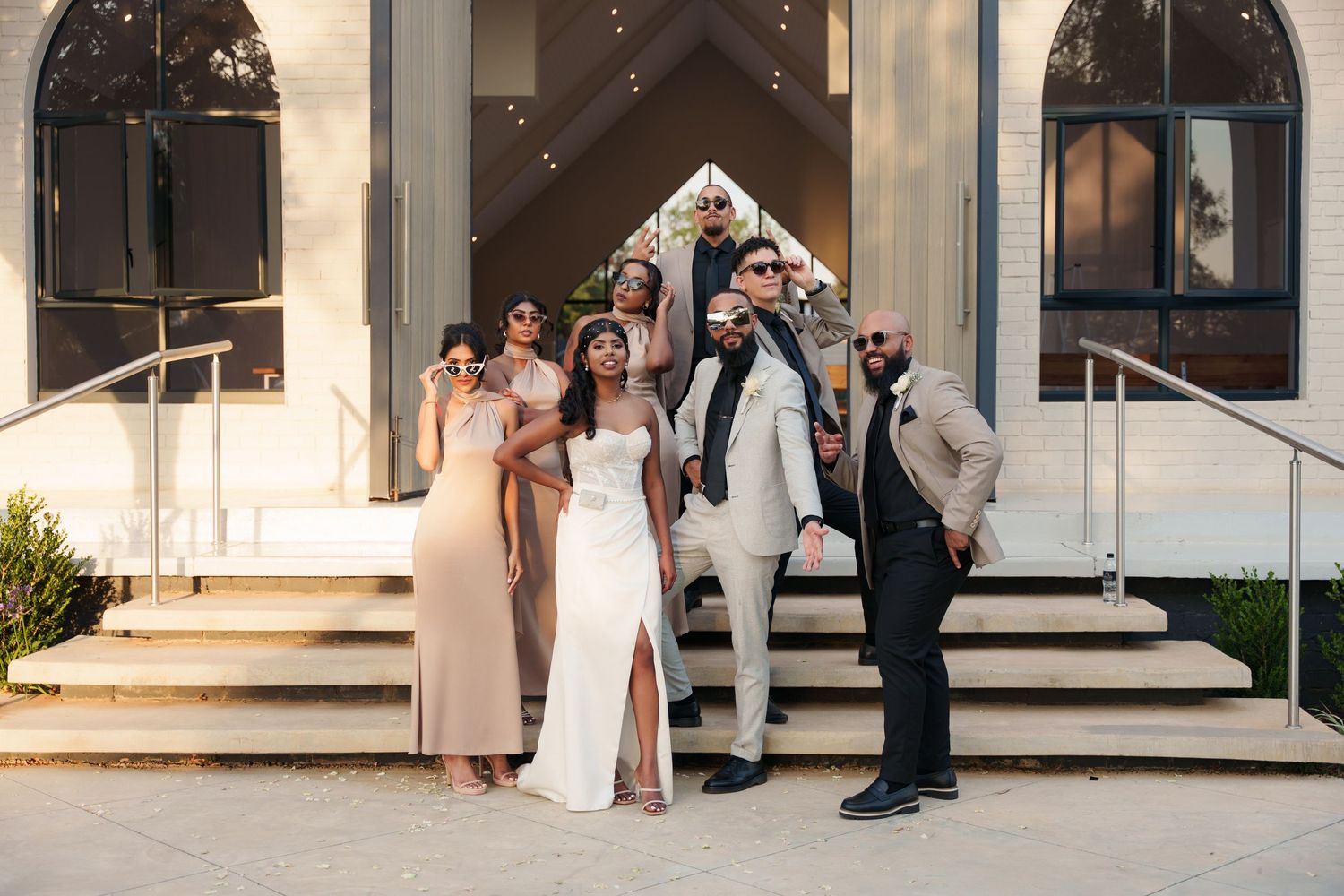 Wedding party poses on church steps in formal attire.