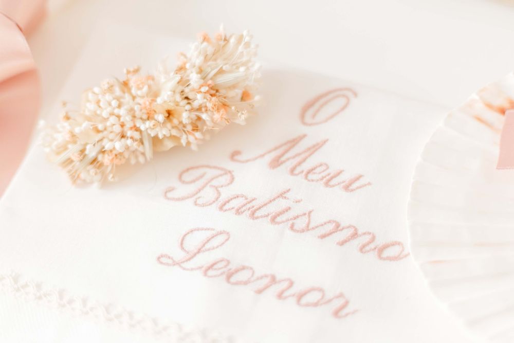 Delicate embroidered text 'Mon Bapteme' in soft pink with floral accents.