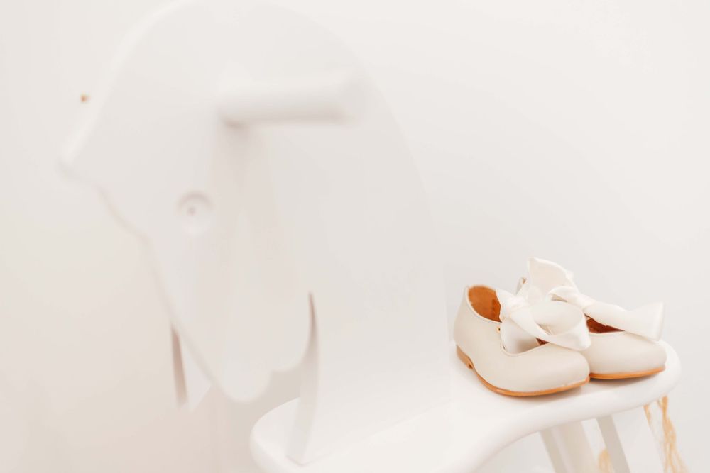 White baby shoes displayed against a light background with soft shadows.
