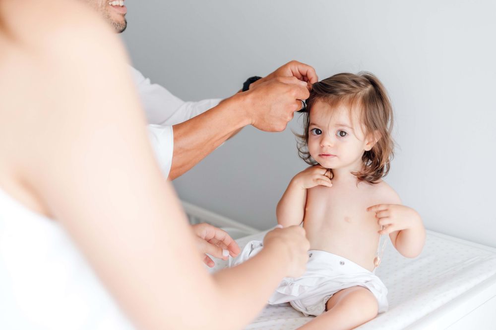 Toddler getting examined while sitting on an examination table.