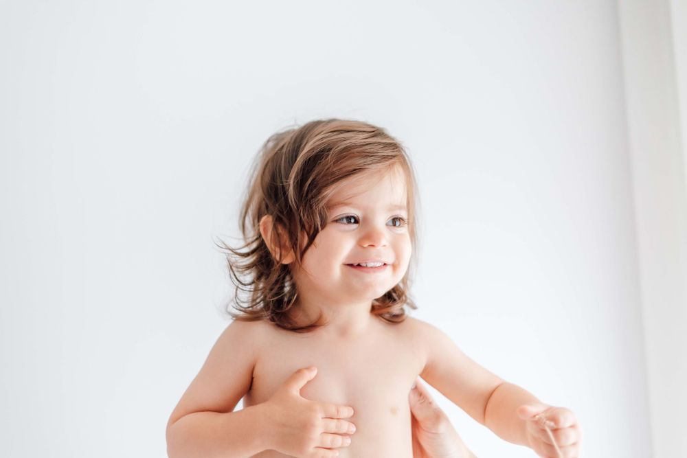 Joyful toddler smiling against a white background during a medical visit.
