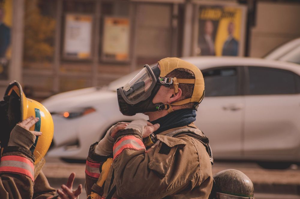 Firefighter in yellow helmet and protective equipment at an incident scene.