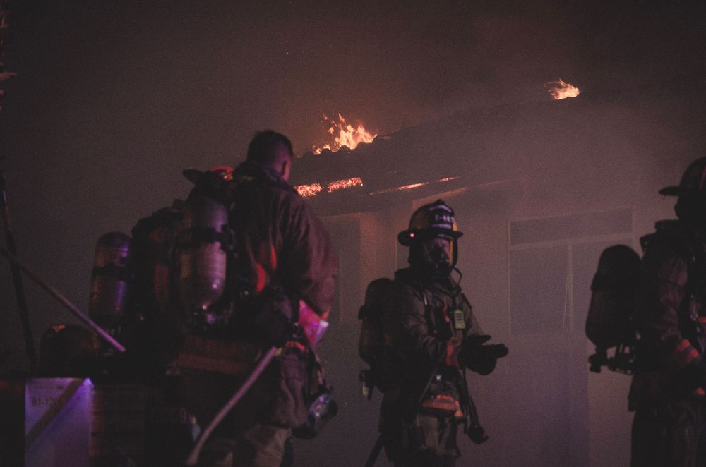 Silhouettes of firefighters working in smoky conditions at night.