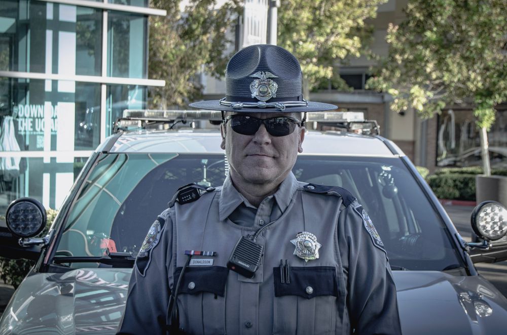 Police officers in dark uniforms standing in front of patrol vehicles.