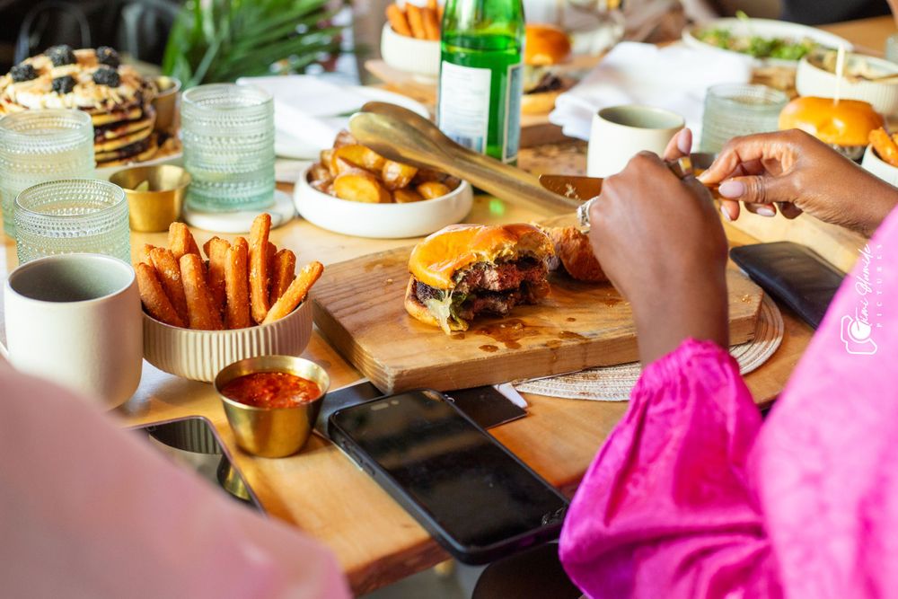 Casual brunch setting with french fries, burgers, and drinks served on wooden boards.