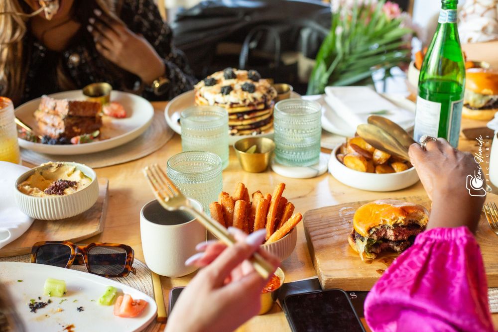 Brunch spread with pancakes, french fries, and colorful drinks on wooden table.
