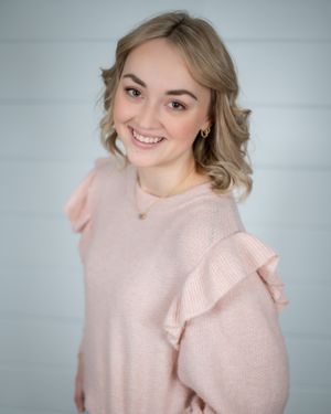Portrait of someone in a pink ruffled sweater against a white background.