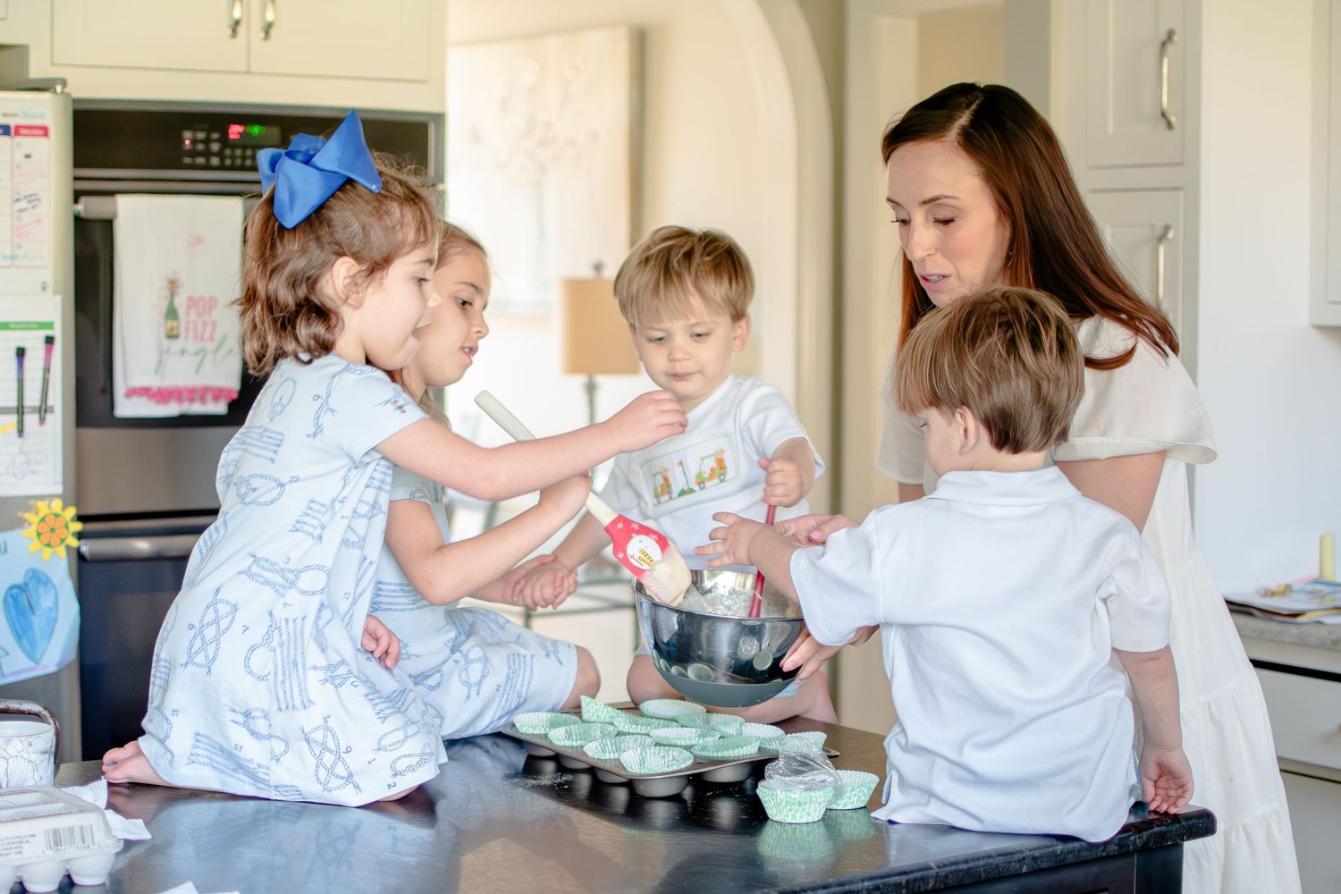 A group preparing cupcakes together in a bright kitchen with blue and white decor.