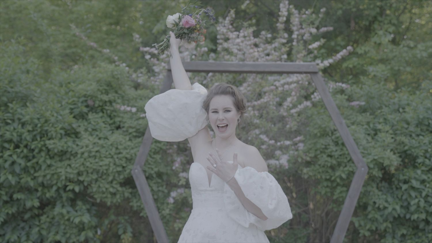 Bride is holding flowers infront of the wedding arch