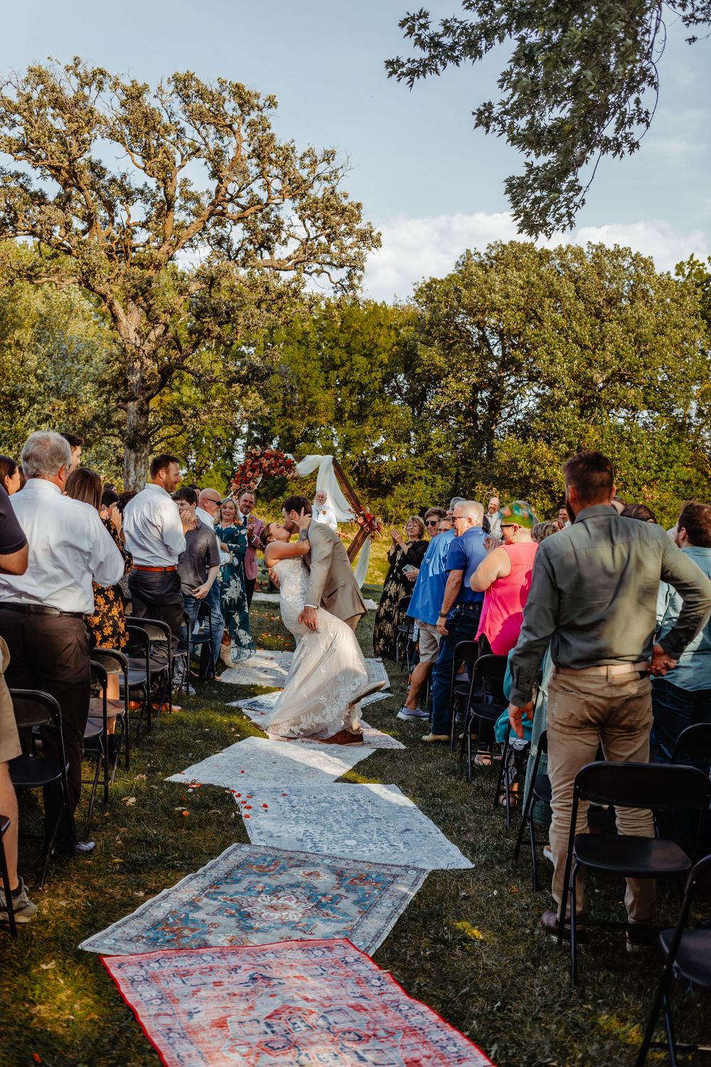 Wedding ceremony aisle decorated with patterned runners and guests seated outdoors.