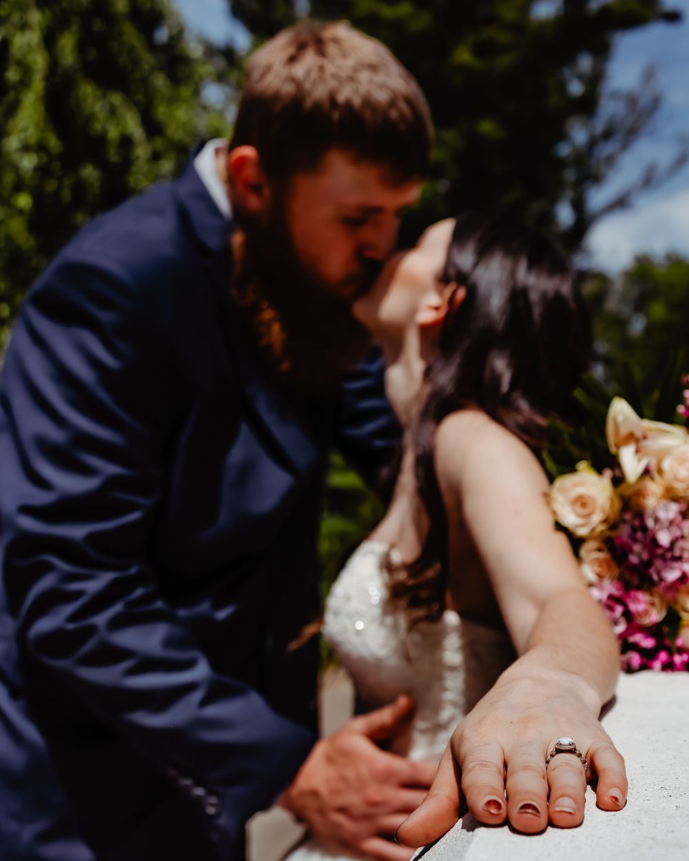 Close-up wedding photo showing rings and floral bouquet details.