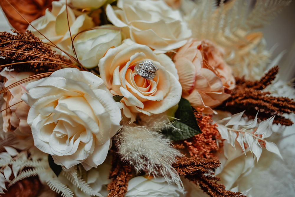 Wedding bouquet featuring cream roses and copper-colored dried flowers.
