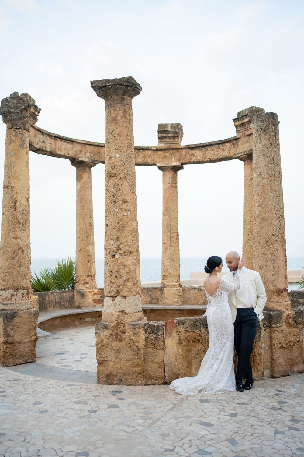 Stone columns create an architectural frame against a coastal backdrop.