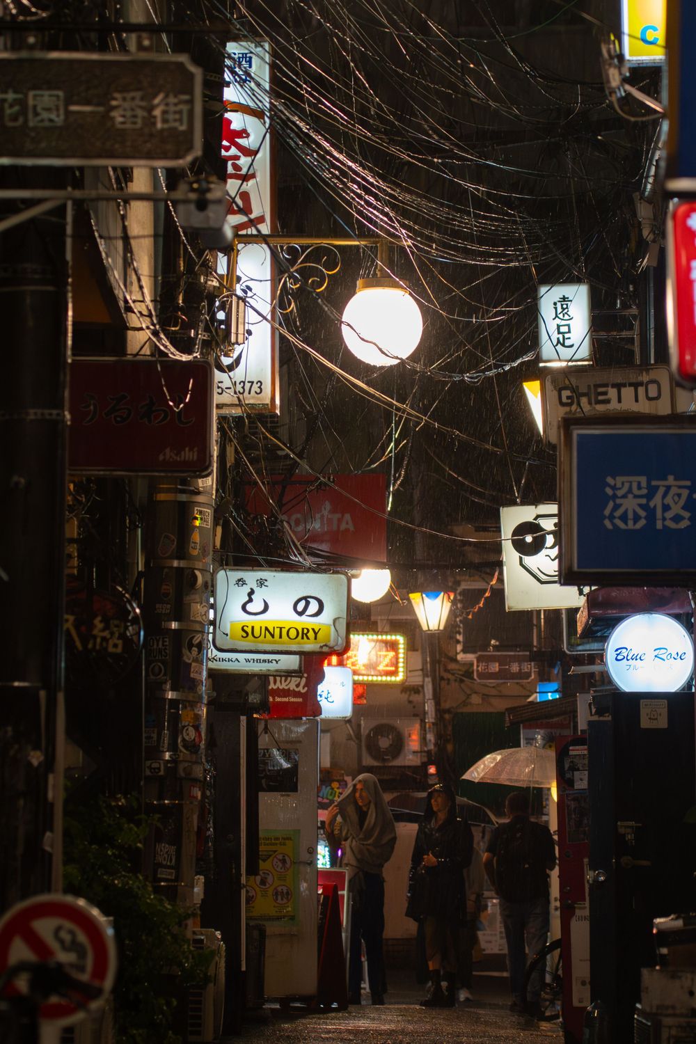 Atmospheric alley in Japan with glowing lanterns and neon signs at night.