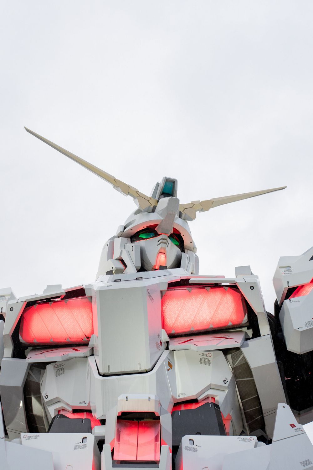 Large white and red mechanical robot statue against cloudy sky.