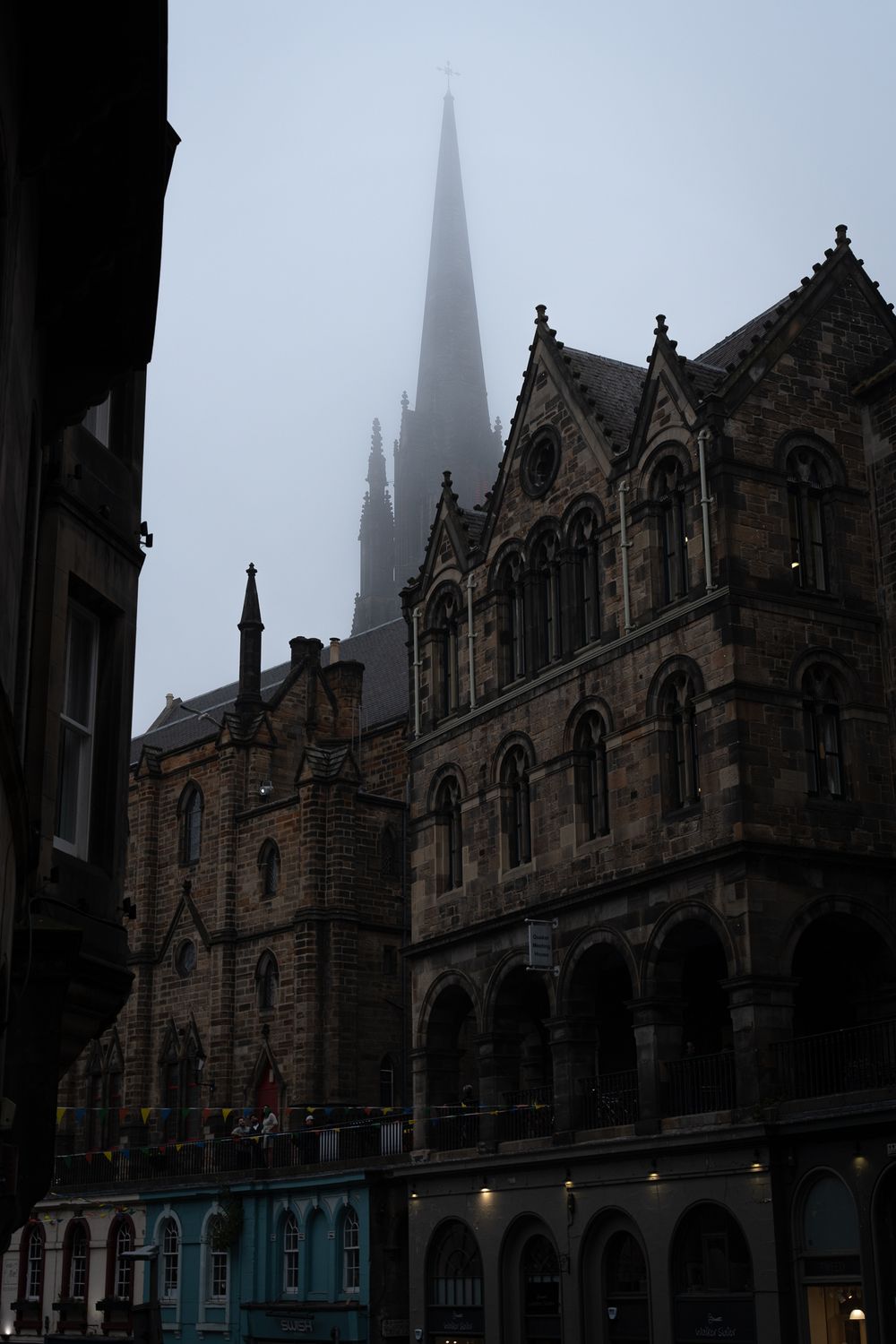 Gothic cathedral spire shrouded in mist with ornate stone architecture in the foreground.