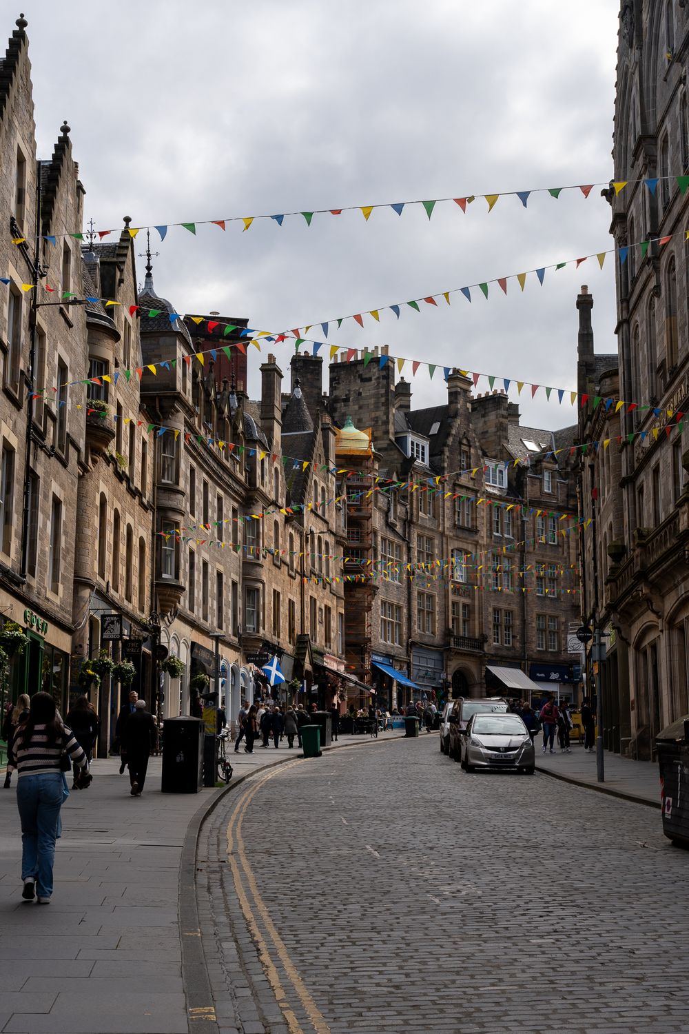 Historic Edinburgh street with Victorian architecture and colorful bunting strung overhead.