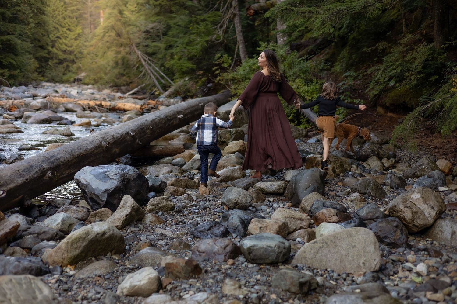 Samantha and her kids play in a dry river with large rocks during a family photo session near Issaqua.