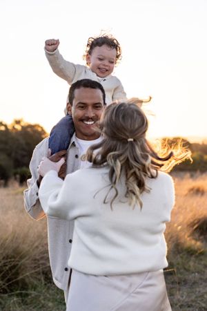 Family spinning in circles and playing with toddler on dads shoulders for a family photo shoot at Rouse Hill Regional Park, Sydney.