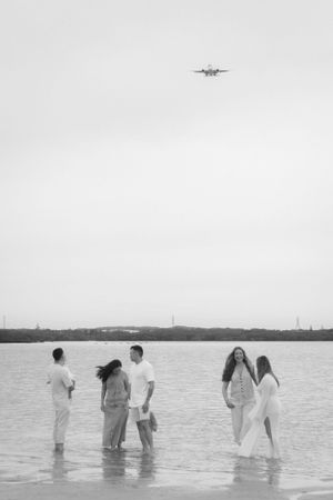 Family stand in the water as the plane fly's over them during a candid family photo shoot at Cronulla Beach, Sydney.