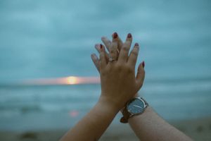 Hands clasped together against a moody blue sky background.