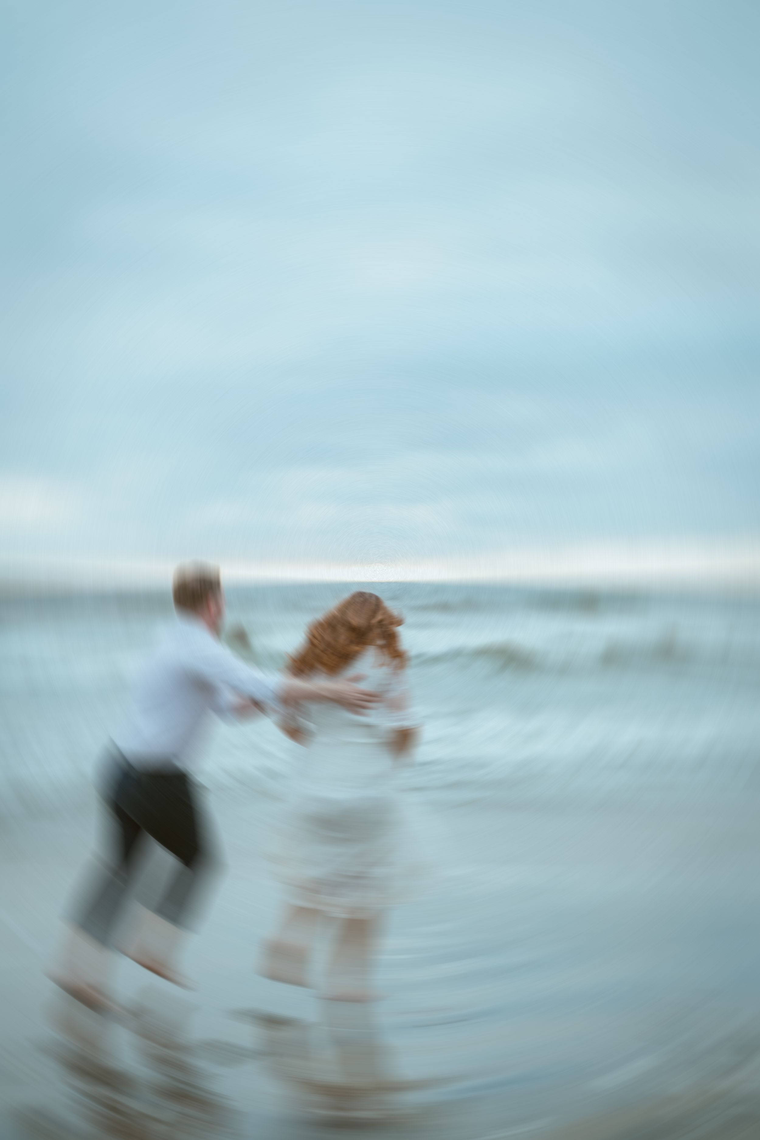 Motion blur captures a romantic dance on the shoreline.