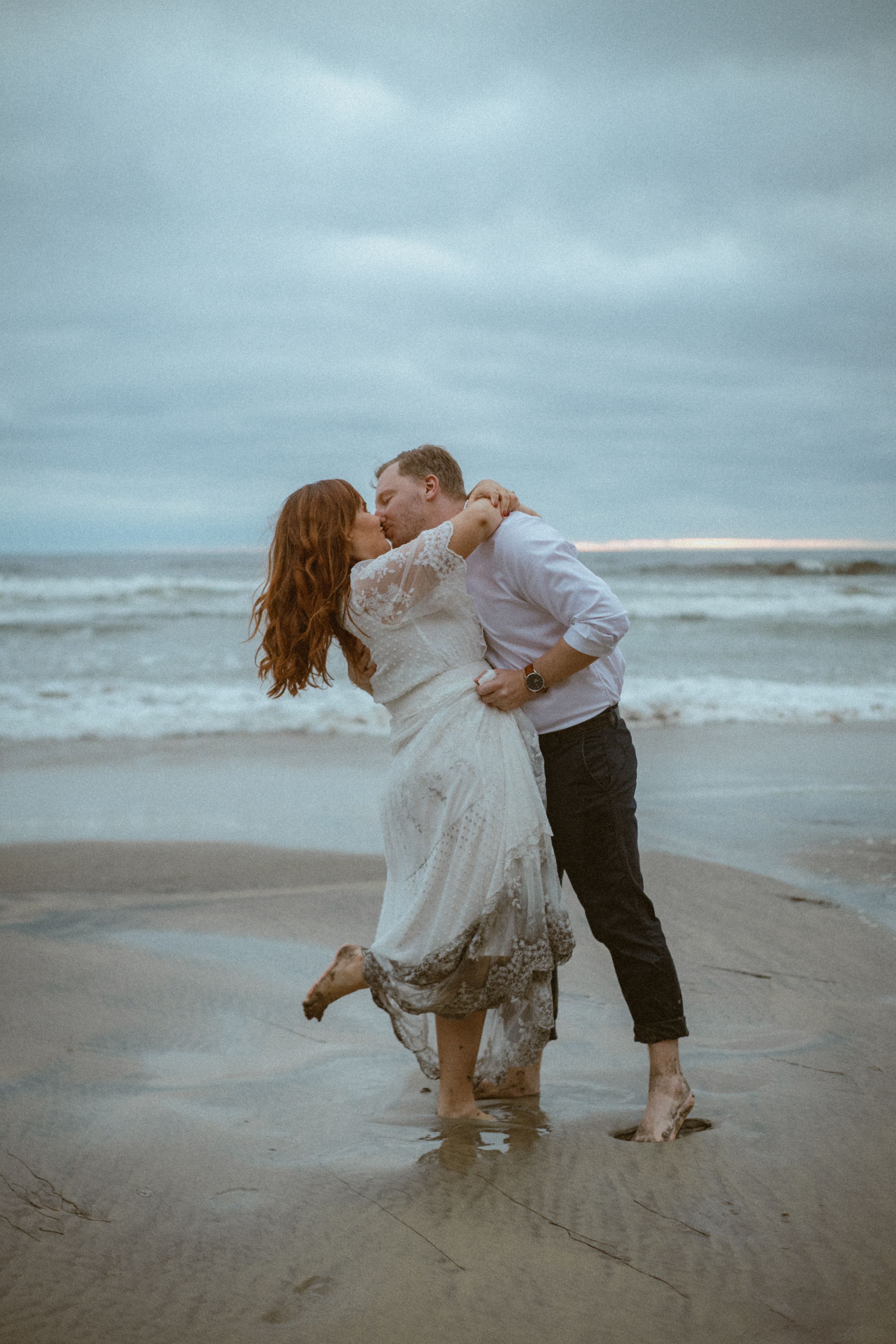 A couple spins joyfully in the shallow ocean waves.