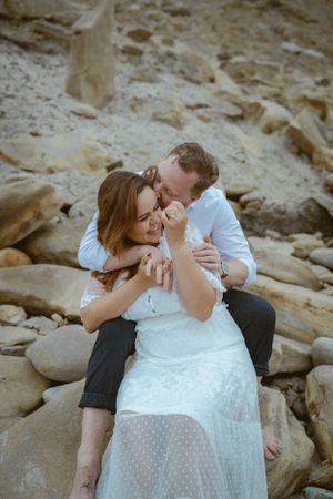 An intimate moment shared between a couple on rocky coastal terrain.