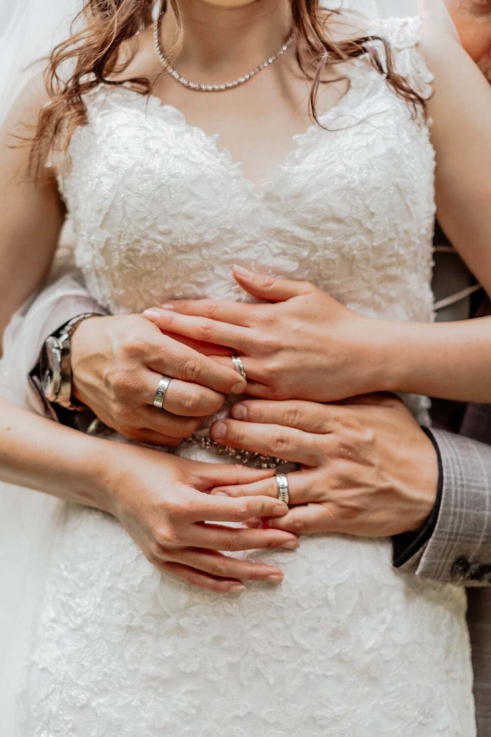 below shoulder bride and groom holding each other displaying wedding rings