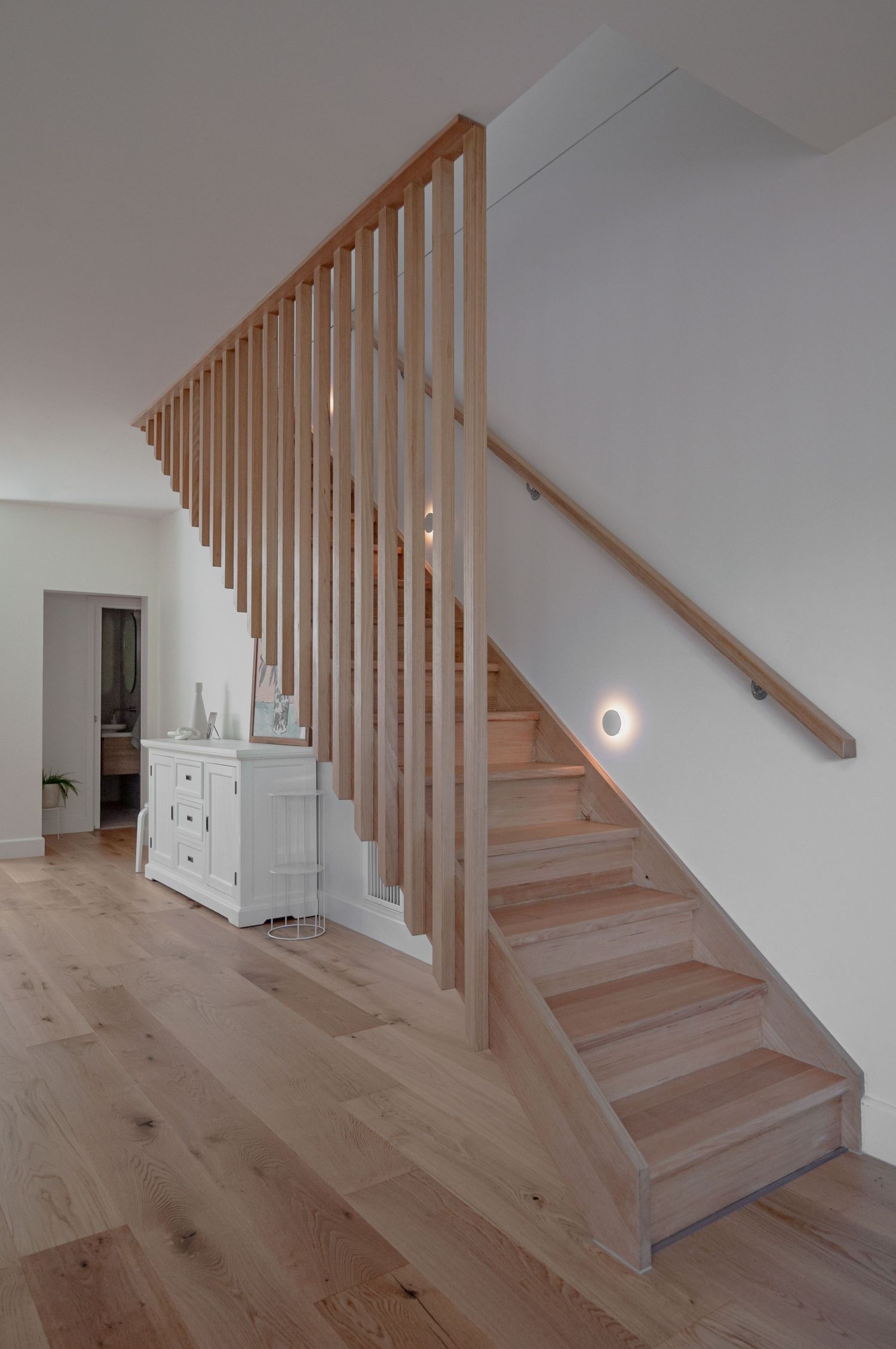 Wooden staircase with modern balustrade and white walls showcasing minimalist interior design.