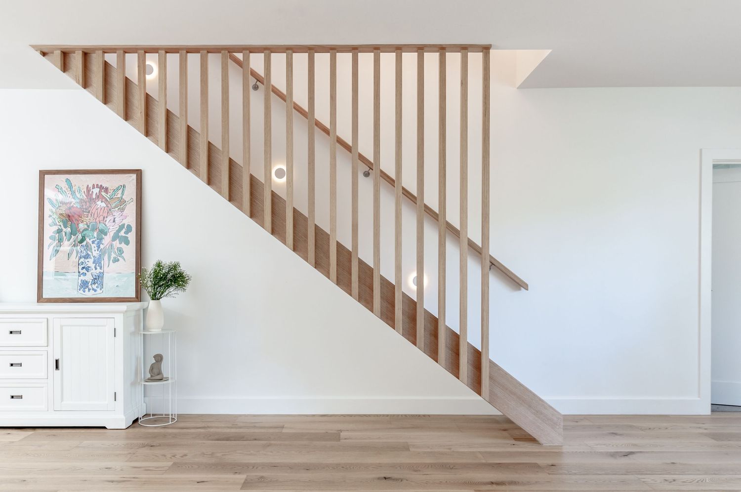 Minimalist staircase with wooden railings and white walls in modern home interior.