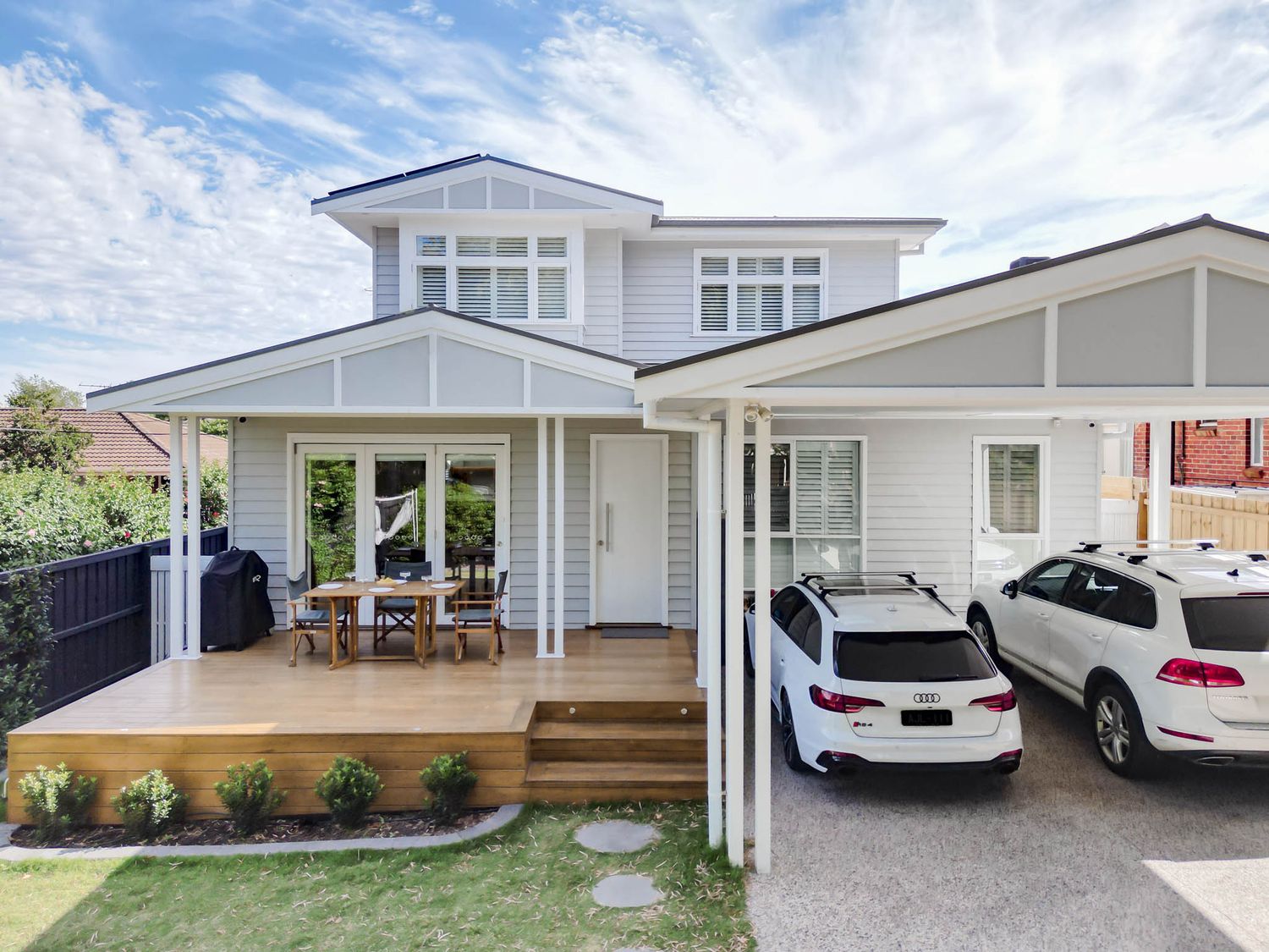 Modern Hampton-style home exterior with white facade, timber deck and covered carport.