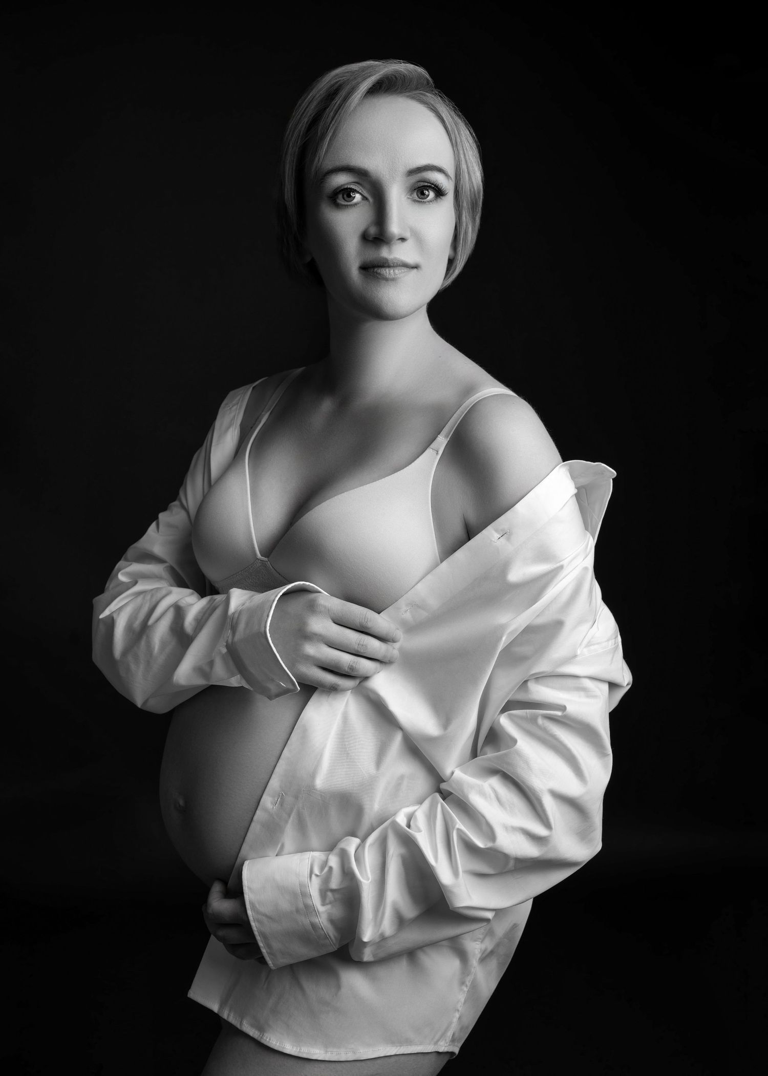 a pregnant mother makes direct eye contact while holding a white button to her shoulder