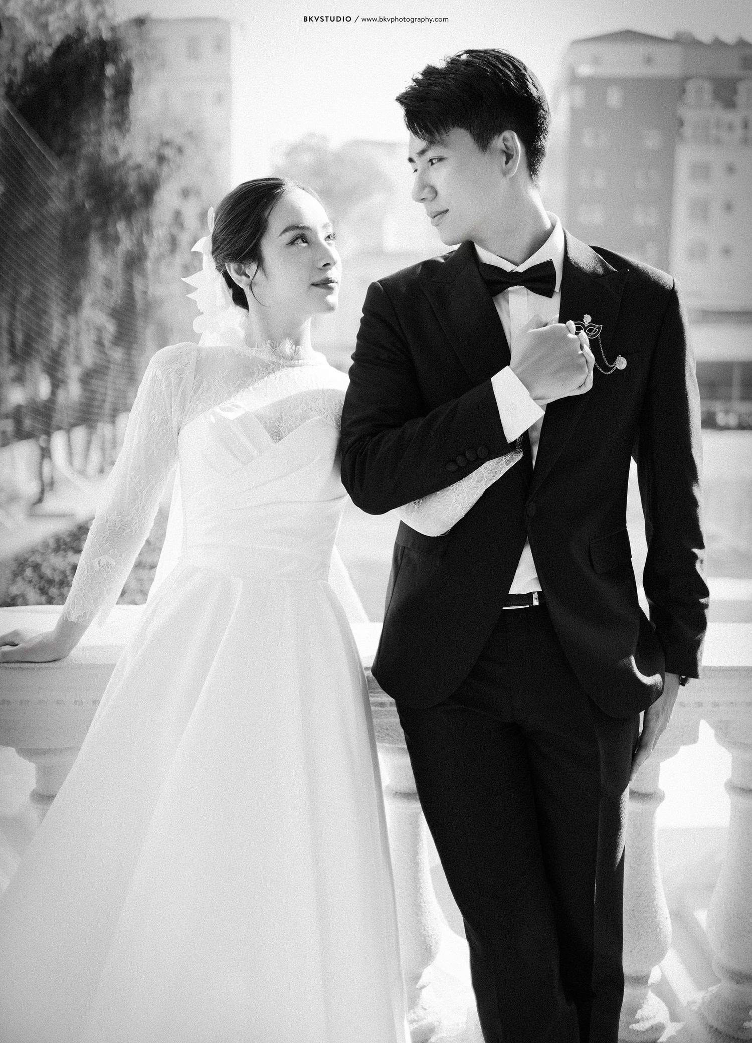 Black and white wedding photo of a couple in formal attire sharing an intimate moment.