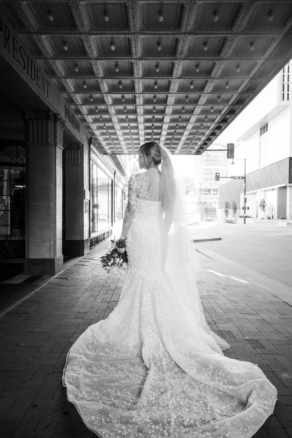 Elegant bridal portrait showcasing lace wedding dress with long train under architectural ceiling.